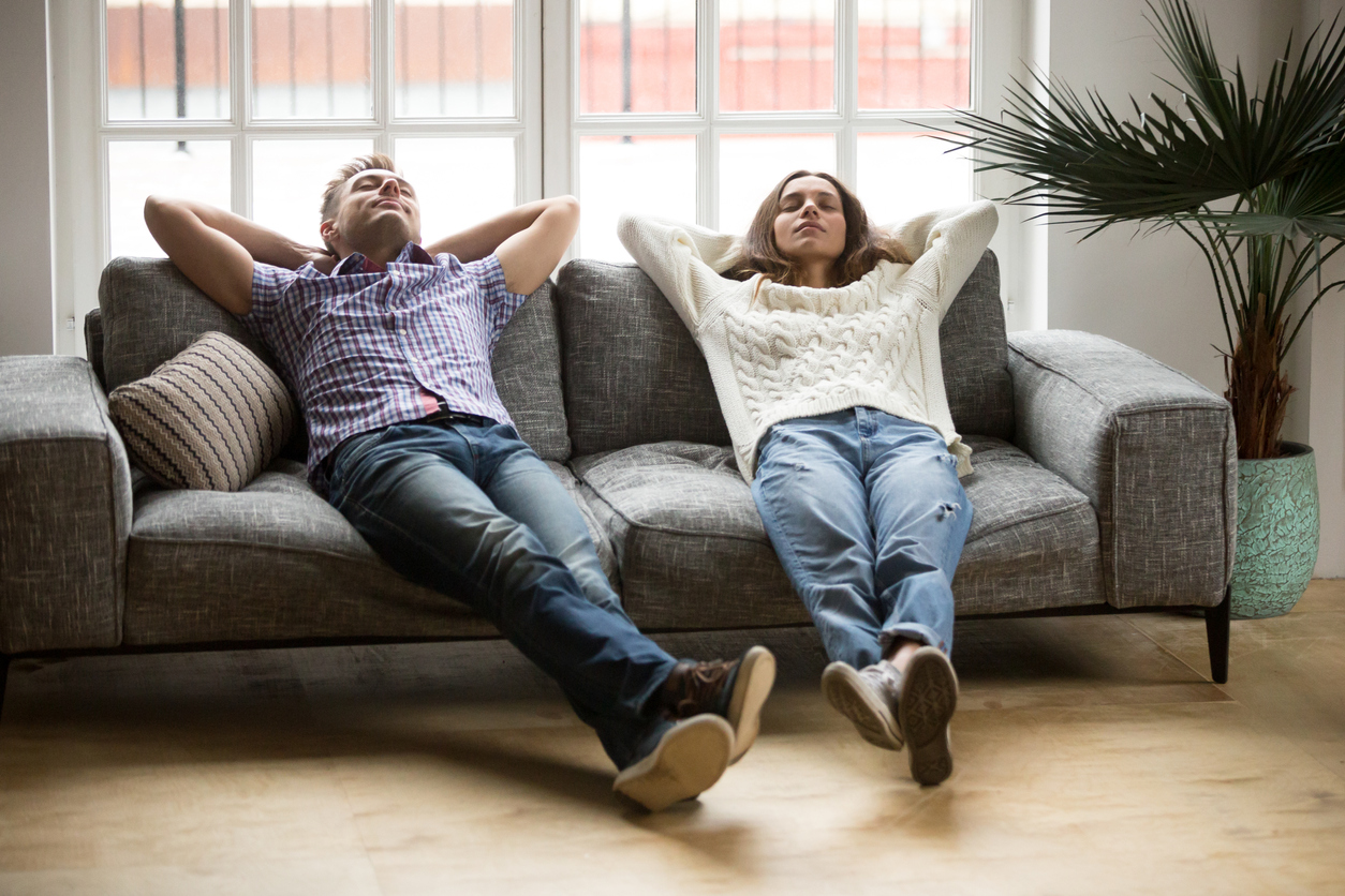 A young couple relaxing on a couch in their home.