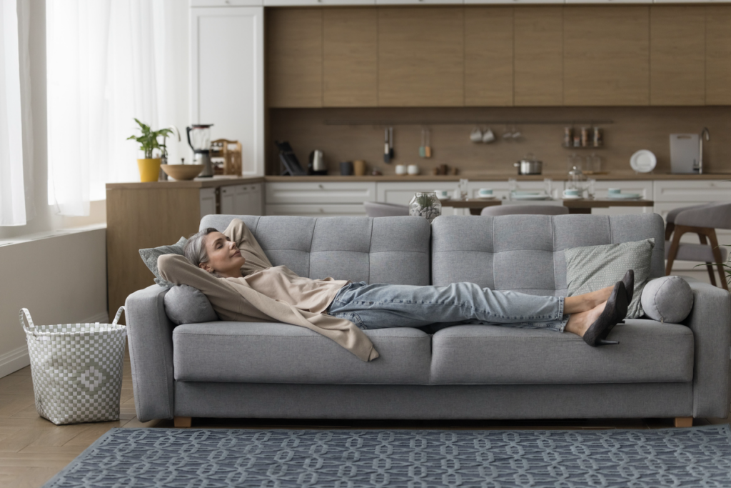 Mature woman lying on her couch relaxing, eyes closed.