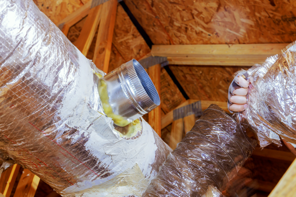 Insulated ductwork being installed in a residential attic